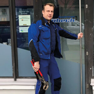 Handwerker mit Zange öffnet Tür.