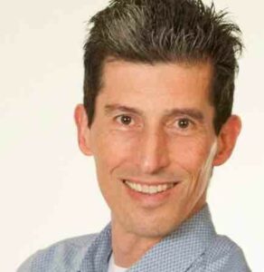 Lächelnder Mann mit grauen Haaren.